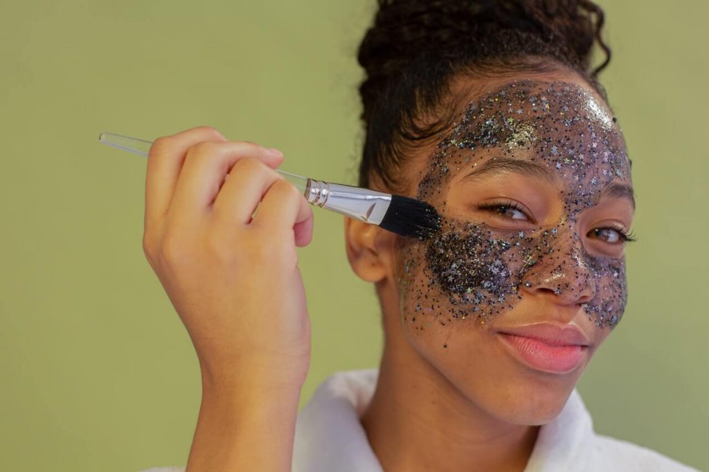 Woman using glittery charcoal face scrub