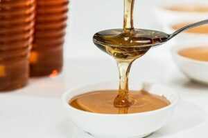 a spoon of honey dripping into a small bowl filled with honey.