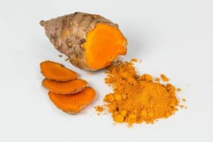 Turmeric plant with slices and powder in orange color