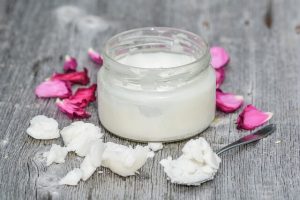Coconut cream in a small jar with rose petals around
