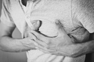 A man pressing on his heart indicating heart pain